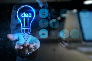 businessman hand draws lightbulb with new computer interface photo