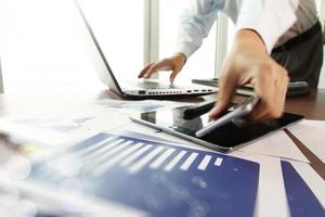 business documents on office table with smart phone and digital tablet and man working in the background photo