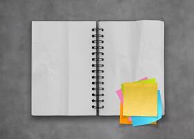 sticky notes with open blank note book on desk top texture photo