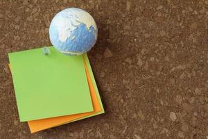 hand drawn texture globe  with pin and sticky note on cork board as concept photo