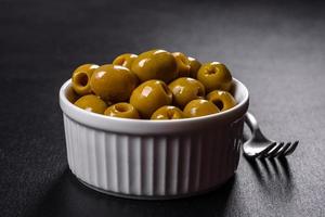 Beautiful pickled green olives on a dark concrete background photo