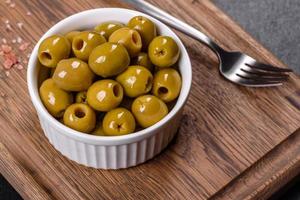 Beautiful pickled green olives on a dark concrete background photo