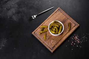 Beautiful pickled cucumbers of small size on a dark concrete background photo
