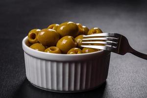 Beautiful pickled green olives on a dark concrete background photo