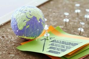 hand drawn texture globe with pin and business graph sticky note on cork board as concept photo