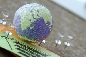 hand drawn texture globe with pin and business graph on sticky note on cork board as concept photo