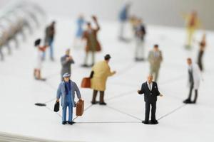 close up of miniature people with social network diagram on open notebook on wooden desk as social media concept photo