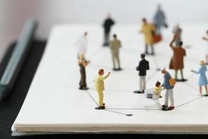 close up of miniature people with social network diagram on open notebook on wooden desk as social media concept photo