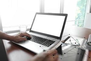 designer hand working with stylus and digital tablet and laptop on wooden desk in office photo