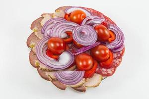 View from the top sausage and cold cuts with onions and cherry tomatoes photo