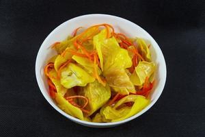 Pickled cabbage with curry and carrots in a plate on a black background top view photo