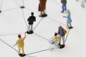 close up of miniature people with social network diagram on open notebook on wooden desk as social media concept photo