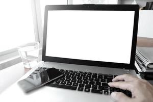 Cerca de la mano del hombre de negocios trabajando en la computadora portátil de pantalla en blanco en el escritorio de madera como concepto foto