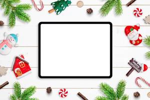 Tablet mockup on white wooden desk, surrounded by Chrismtas decorations. Top view, flat lay composition photo