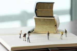 Creative idea concept - miniature photographer with vintage golden book on open paper notebook photo