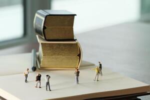 concepto de idea creativa: fotógrafo en miniatura con un libro dorado vintage en un cuaderno de papel abierto foto