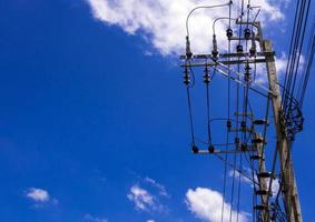 poste eléctrico y cable bajo nubes y cielo azul foto