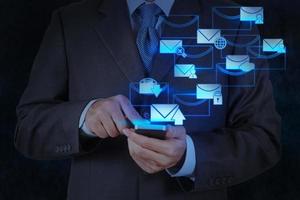 La mano del hombre de negocios usa una computadora de teléfono inteligente con un icono de correo electrónico foto