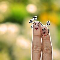 the happy finger couple in love with painted smiley and sing a song on flower nature background photo