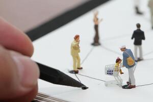 close up of miniature people with social network diagram on open notebook on wooden desk as social media concept photo