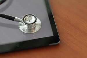 Studio macro of a stethoscope and digital tablet with shallow DOF evenly matched abstract on wood table background copy space photo