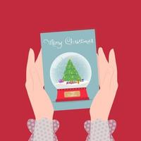 Christmas illustration, female hands are holding a greeting card with a snowy glass ball and the inscription Merry Christmas. vector