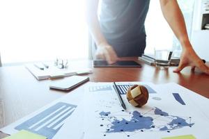 Moving Image of Business creative designer working wooden texture globe with smart phone on business document in office desk as internet concept photo