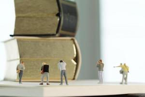 concepto de idea creativa: fotógrafo en miniatura con un libro dorado vintage en un cuaderno de papel abierto foto