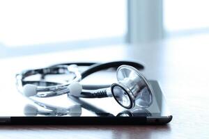 Studio macro of a stethoscope and digital tablet with shallow DOF evenly matched abstract on wood table background copy space photo