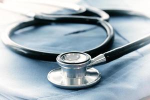 Stethoscope with blue doctor coat on wooden table with shallow DOF evenly matched and background photo