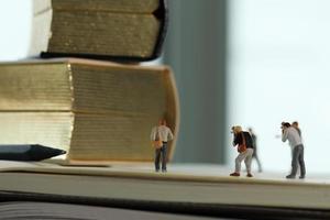 concepto de idea creativa: fotógrafo en miniatura con un libro dorado vintage en un cuaderno de papel abierto foto