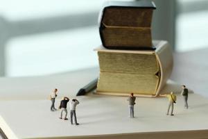 concepto de idea creativa: fotógrafo en miniatura con un libro dorado vintage en un cuaderno de papel abierto foto