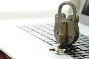 Internet security concept-miniature businessman stand on old key and padlock on laptop computer keyboard photo