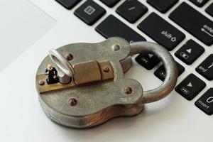 Internet security concept-miniature businessman stand on old key and padlock on laptop computer keyboard photo