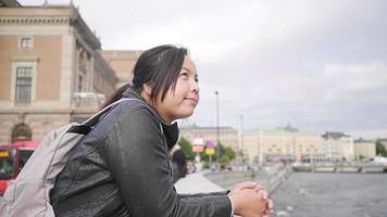 Asian woman standing and seeing beautiful view of river in Sweden, standing by the river. traveling abroad on holiday. City background