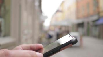 cierra las manos de una mujer asiática de pie y usando un teléfono inteligente en la ciudad, saliendo a caminar por la calle en suecia. viajar al extranjero en vacaciones largas video