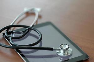 Studio macro of a stethoscope and digital tablet with shallow DOF evenly matched abstract on wood table background copy space photo