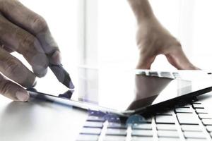 designer hand working with stylus and digital tablet and laptop on wooden desk in office photo