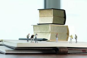 concepto de idea creativa: fotógrafo en miniatura con un libro dorado vintage en un cuaderno de papel abierto foto