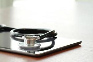 Studio macro of a stethoscope and digital tablet with shallow DOF evenly matched abstract on wood table background copy space photo