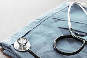 Stethoscope with blue doctor coat on wooden table with shallow DOF evenly matched and background photo