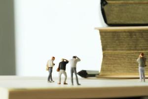 Creative idea concept - miniature photographer with vintage golden book on open paper notebook photo