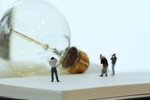 Creative idea concept - miniature photographer with vintage light bulb on open paper notebook photo