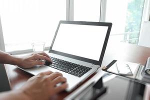 Close up of business man hand working on blank screen laptop computer on wooden desk as concept photo