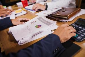 Businessmen are using calculators and analysis business data and and graph financial diagram working  at the meeting. photo