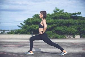 mujer atlética asiática calentándose y joven atleta sentada en un ejercicio y estirándose en un parque antes de correr al aire libre, concepto de estilo de vida saludable foto