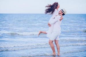 Feliz pareja romántica amante tomados de la mano juntos caminando por la playa foto