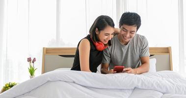 Asian couple lovers listening to music and singing on his bed and happy on relax time photo