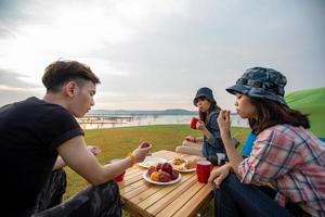 un grupo de amigos asiáticos tomando café y pasando el tiempo haciendo un picnic en las vacaciones de verano. son felices y se divierten en las vacaciones.