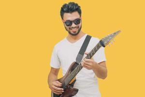 Handsome young asian men playing guitar and  listen music with headphones  isolated on yellow background photo